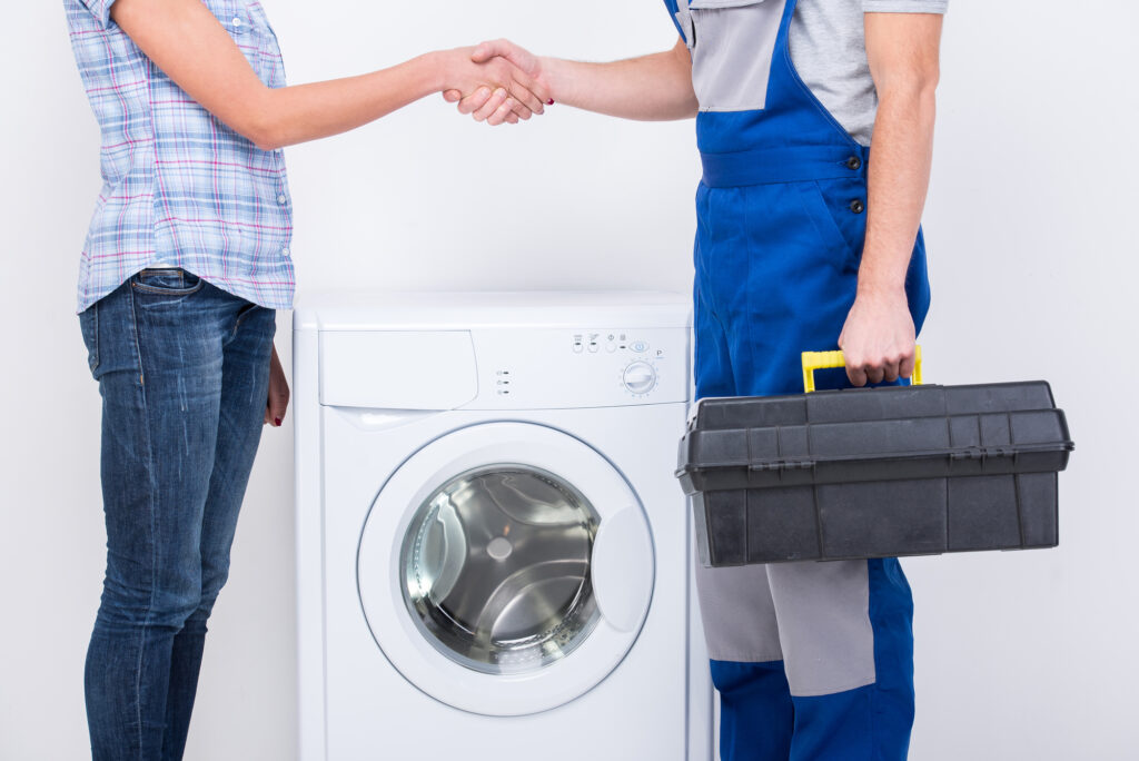 Handshake Of A Lady And Repairman Near The Washing Machine